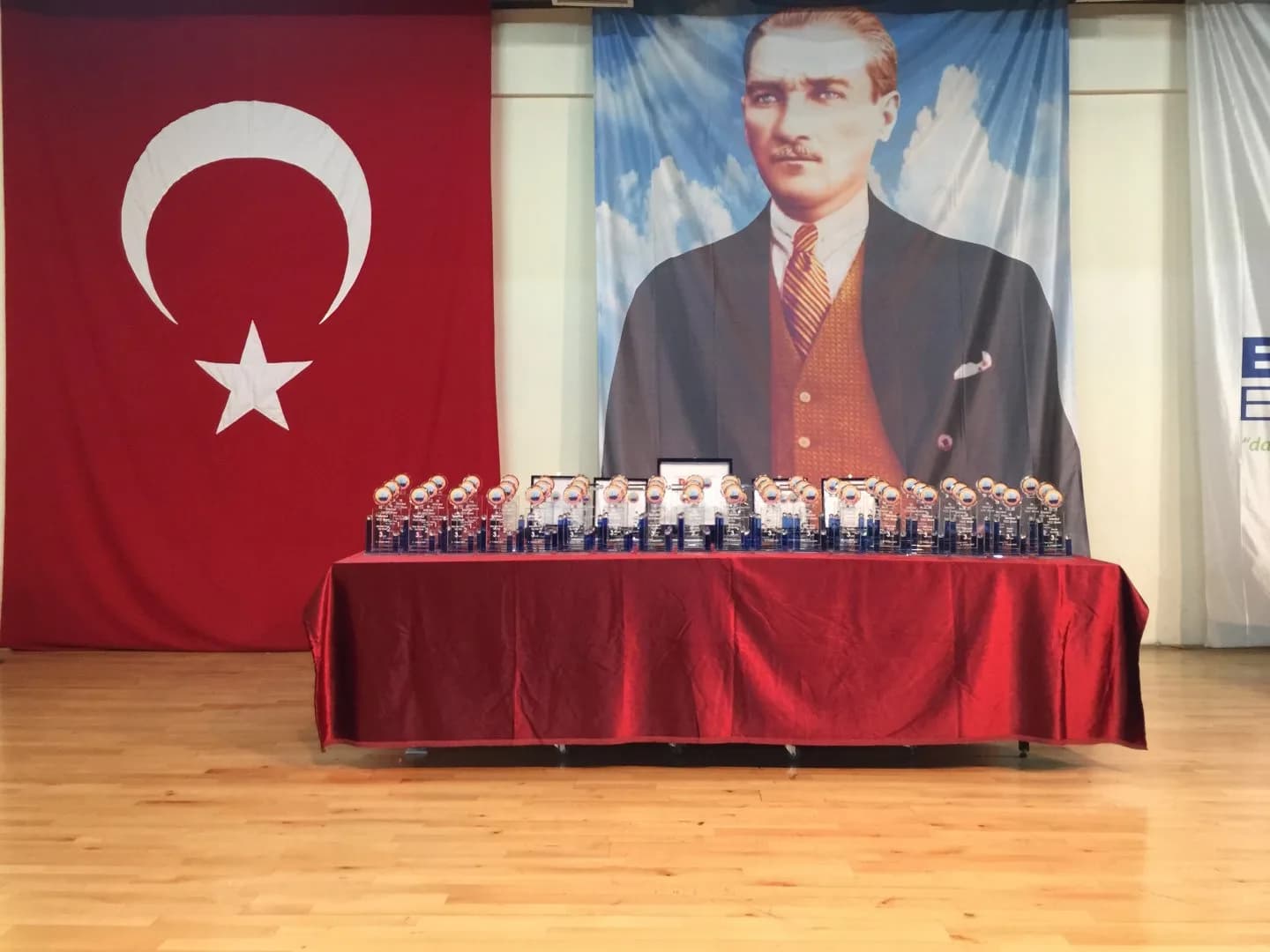 IYCC 2019 show: glass trophies and plaques lined up on a red-covered table on the stage.