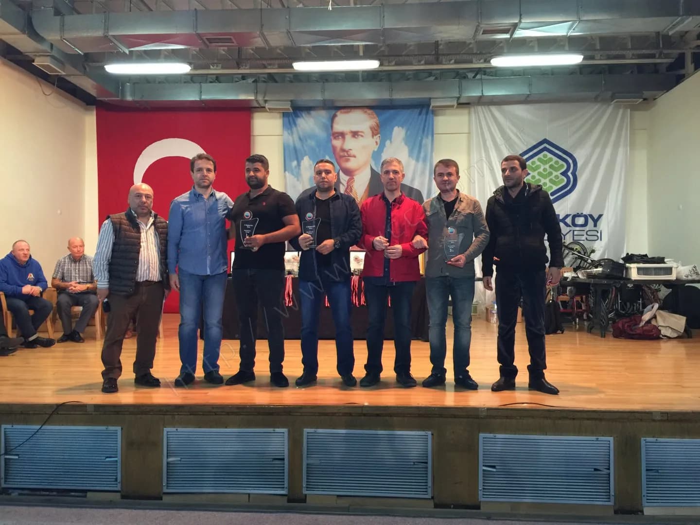 IYCC 2017 ödül töreninde sahnede sekiz kişi; ortadakiler cam plaketler, biri kırmızı ceketli