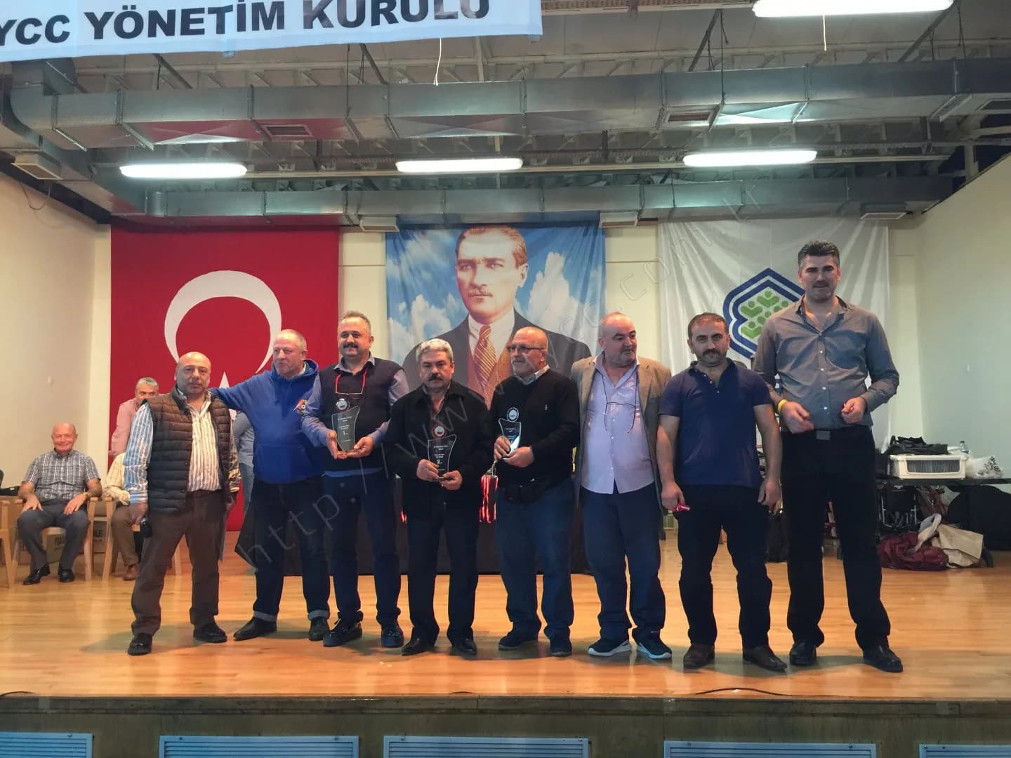 IYCC 2017 ödül töreninde sahnede dokuz kişi, ortadaki üç kişi cam plaketlerini gösteriyor