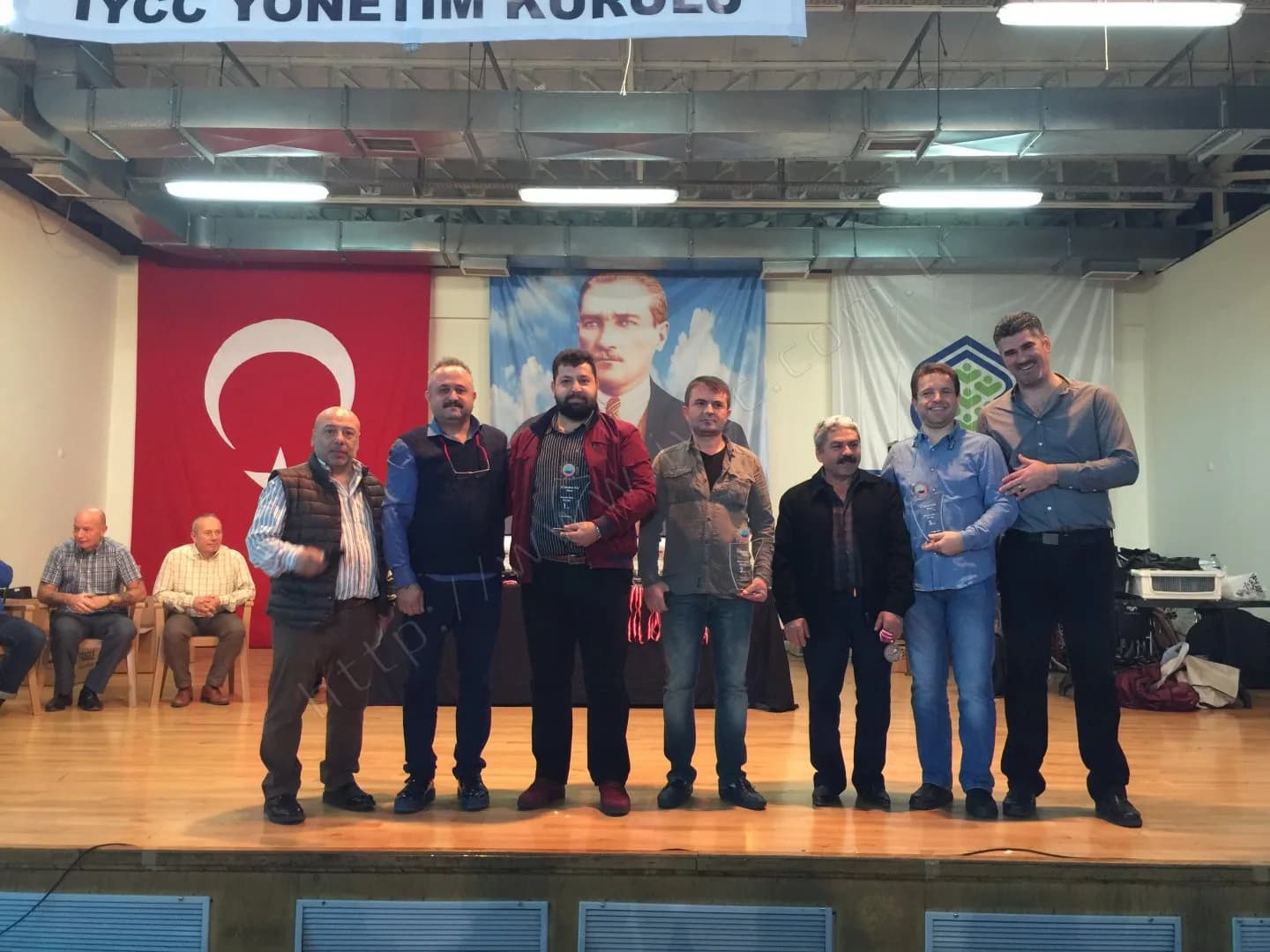 IYCC 2017 ödül töreninde sahnede sekiz kişi, ortada bordo ceketli biri ve yanındakiler plaketlerini tutuyor