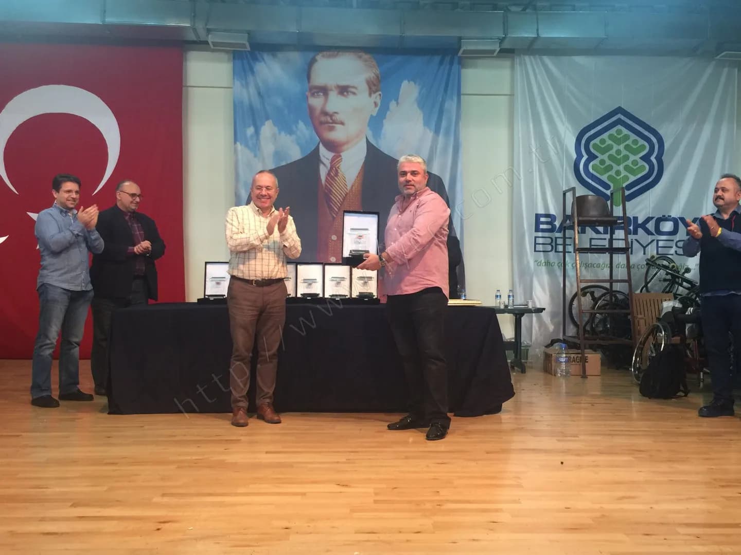 IYCC 2017 ödül töreninde pembe gömlekli katılımcı plaketini alıyor, sahnedekiler onu alkışlıyor