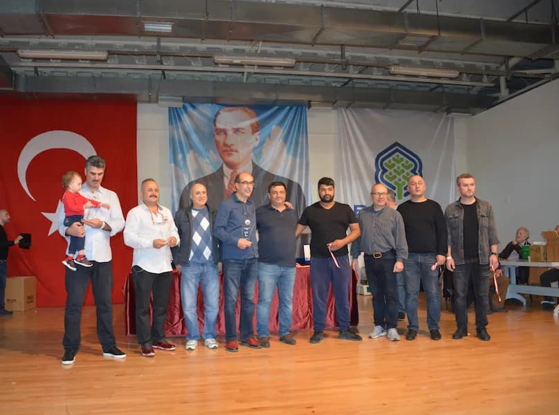 At the IYCC 2018 final, the man on the left holds a small child while others in the group hold medal ribbons