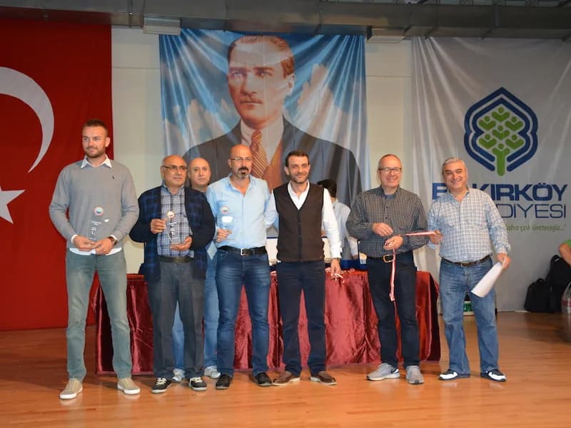 Seven men on stage at the IYCC 2018 final; several hold trophies and medals, and the man on the right holds a certificate