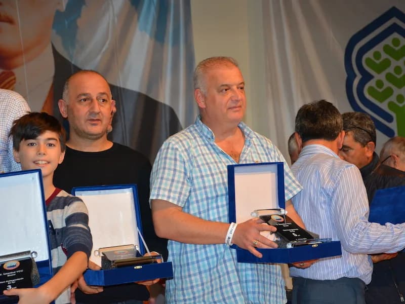 Award winners, including a boy, hold their plaques in open blue boxes at the IYCC 2018 awards ceremony