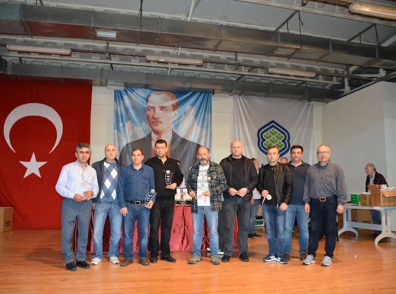 Eleven men stand on stage with trophies and medals at the IYCC 2018 final; a table of award boxes is visible on the right