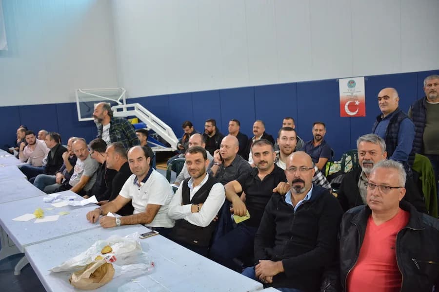 IYCC 2018 yarışmasında spor salonundaki uzun masalarda oturan ve ayakta bekleyen kalabalık bir katılımcı grubu